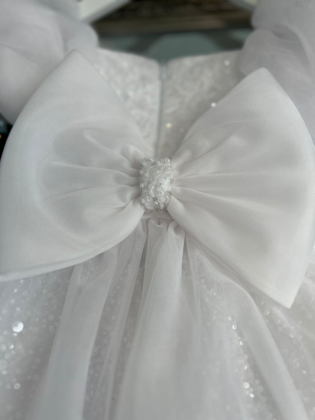 Large fabric bow with glass beads and pearl detailing. Aleena Children’s dress with long bridal train. In white sparkle glass beads and sequins. Perfect for as a christening dress, flower girls dress, baptism outfit, communion dress.
