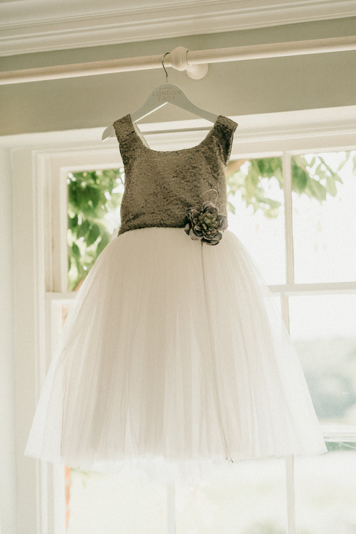Flower girl dress The City Shimmer childrens dress with Silver Sequin Bodice and adjustable straps. A line white tulle skirt and oversized white satin bow and tails at the back. This dress is perfect for Flower girls, little bridesmaids, pageants, wedding guest, birthday parties or any special occasion in your social calendar.