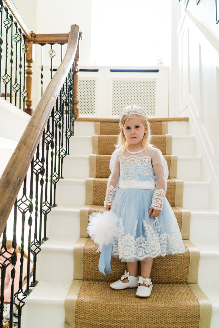 Long Sleeve tulle and embellished lace childrens dress. Baby Blue Bluebell Embellished Lace dress has been handmade to the highest standards for your discerning little lady. A sweet round neck with standout pearl button to close at the back and embellished tulle sleeves are the standout of this elegant blue design, which is completed with a wonderful oversized satin bow on the back. The tulle with lace trim makes this dress totally timeless. Lots of volume in the skirt. Also available in white and pink